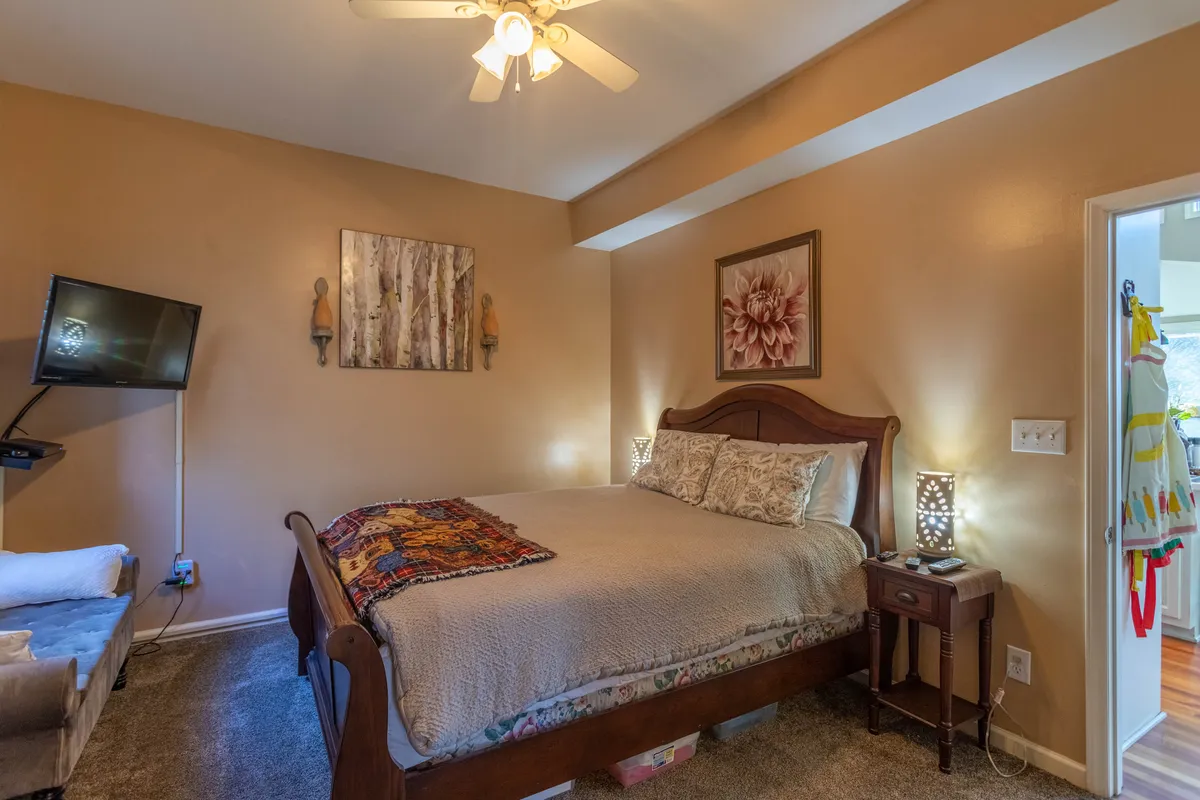A tranquil master suite featuring a plush bed, calming decor, a nightstand, and a wall-mounted HDTV. Ample space and subtle touches create an accessible sanctuary ideal for relaxation after a day of adventure.