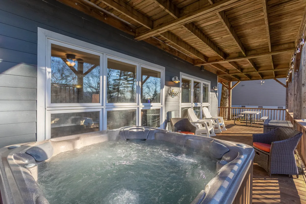 This exterior image showcases the inviting hot tub set on a spacious deck, surrounded by comfortable lounge chairs. The deck provides a tranquil spot to unwind while enjoying the peaceful mountain air, perfectly matching the section's mention of relaxing soaks after a day of exploration. The setting is private, with natural scenery in the background, embodying the retreat's promise of relaxation and connection with nature.