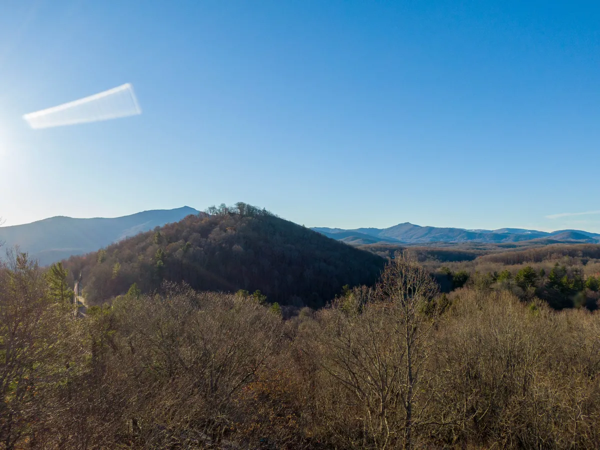 A sweeping view of the mountains and valleys under a clear sky, this image captures the tranquil natural beauty surrounding Misty Mountain Hideaway. The scenery invites guests to imagine peaceful mornings on the porch with mountain views, as referenced in the section.